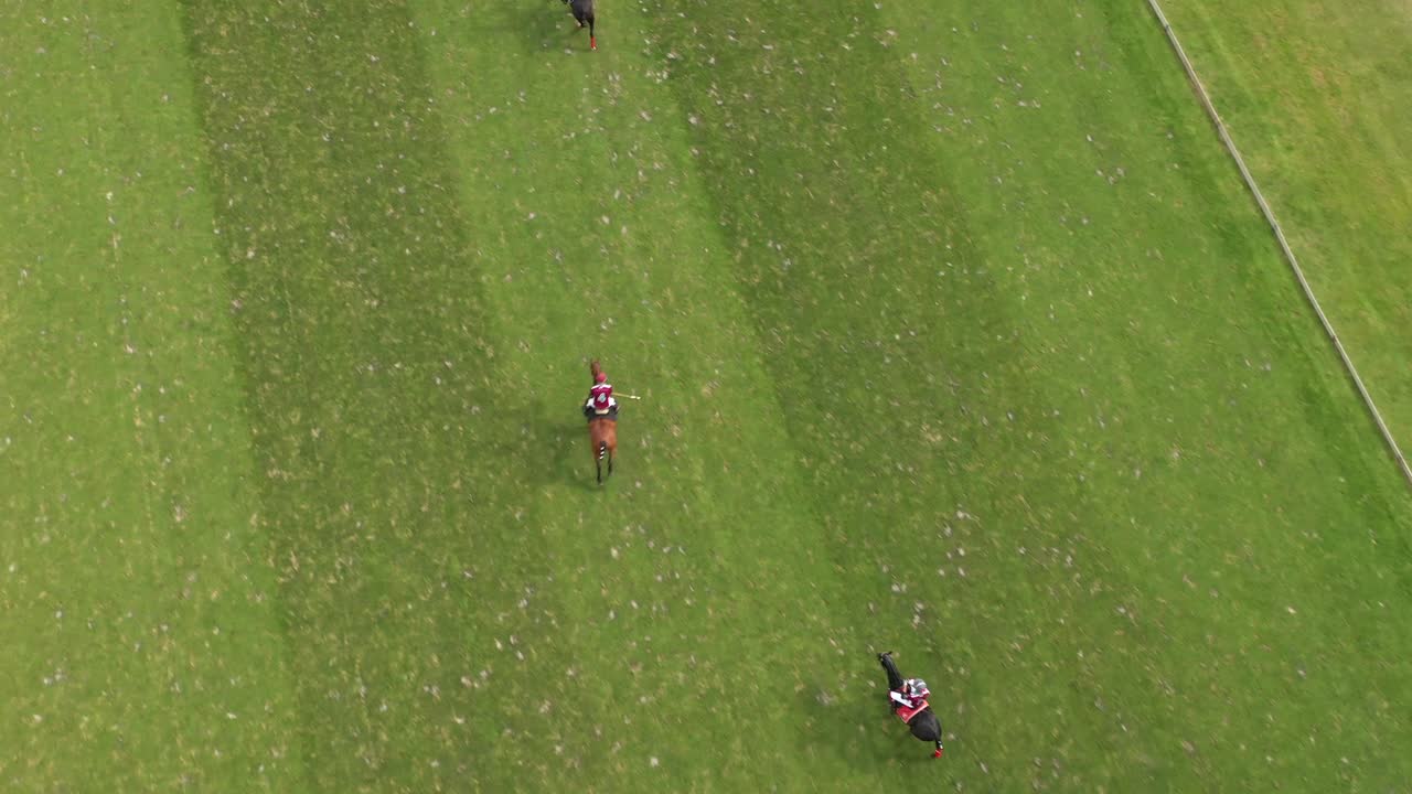 High angle aerial drone shot captures polo players on horseback competing across a vast, striped green field at prestigious Chantilly Polo Club, France