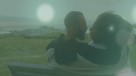 Animation-of-light-spots-over-african-american-couple-at-beach