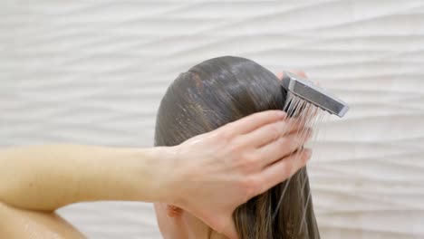 woman washing her hair with shower, water. close up.back view of beautiful naked young woman taking shower in bathroom. beauty spa concept.