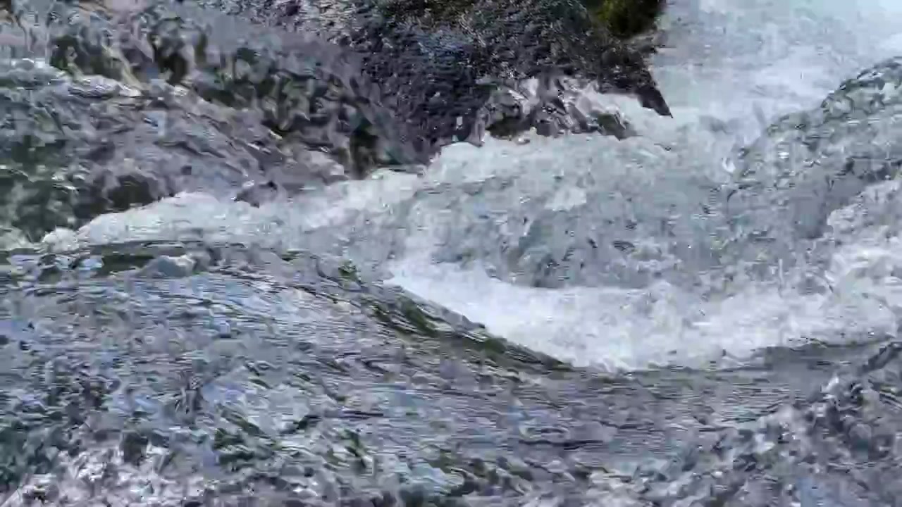 Acqua cristallina di ruscello di montagna che scorre su rocce scure