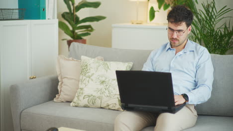 Nachdenklicher-Geschäftsmann,-Der-Zu-Hause-Auf-Dem-Sofa-Sitzt-Und-Am-Laptop-Arbeitet