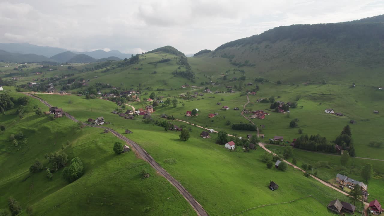 el pueblo de sirnea enclavado entre verdes colinas bajo un cielo nublado, de día, vista aérea