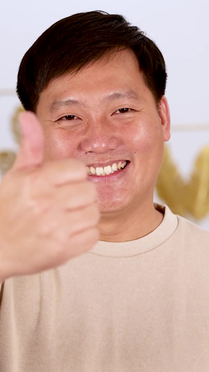 Un uomo asiatico allegro fa un gesto positivo con il pollice in su in un primo piano luminoso e verticale.