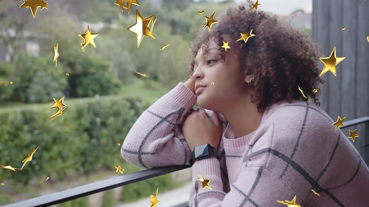 Shot starting golden stars drifting across face, woman leaning balcony rail, reflecting for health