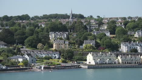 the row of cottages, road and church the view from the ocean approaching cobh, in cork, ireland