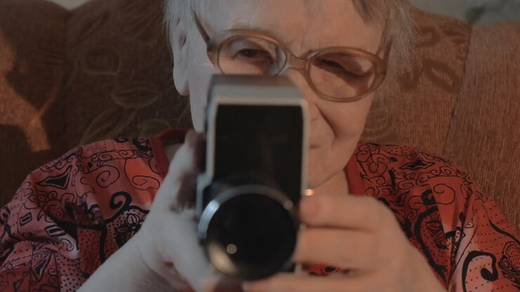 ältere frau, die mit einer retro-videokamera dreht