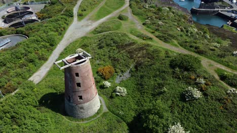 Puerto-Amlwch-Ladrillo-Rojo-En-Desuso-Molino-De-Viento-Abandonado-Vista-Aérea-Norte-De-Anglesey-Gales-Inclinar-Hacia-Arriba-Descender-Para-Revelar-El-Puerto