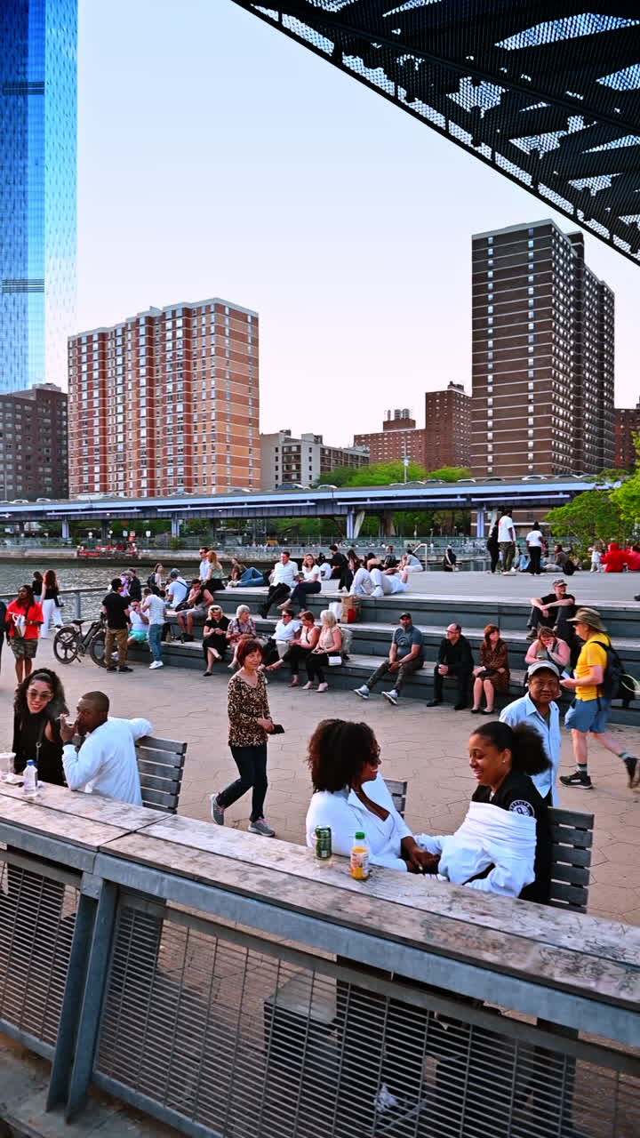 New York, USA, 8 October 2025: Pier by the East River. People gather on a pier by the East River with Manhattan skyline