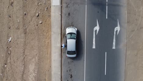 Drohnen-Topdown-Video-Einer-Person,-Die-Aus-Einem-Silbernen-Auto-Steigt