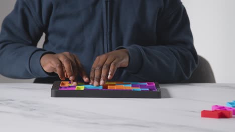 close up of boy on asd spectrum solving shape puzzle on white background