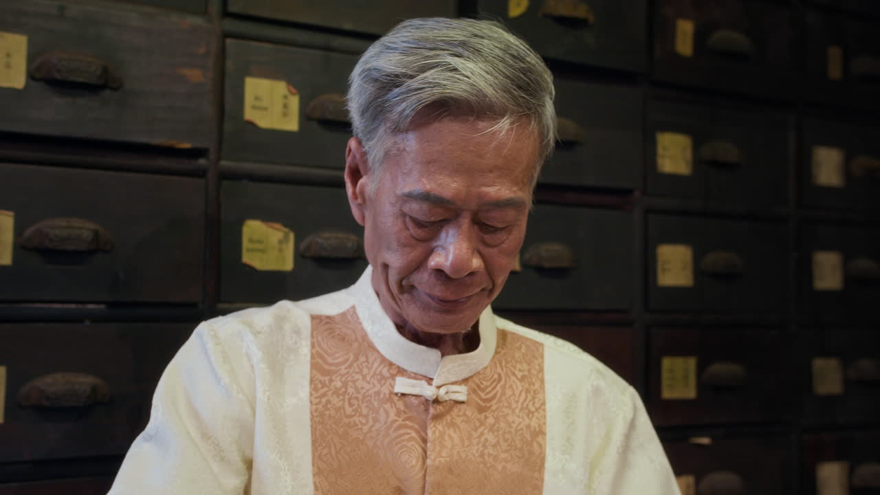 Aged Chinese Druggist Mixing Herbs at Apothecary