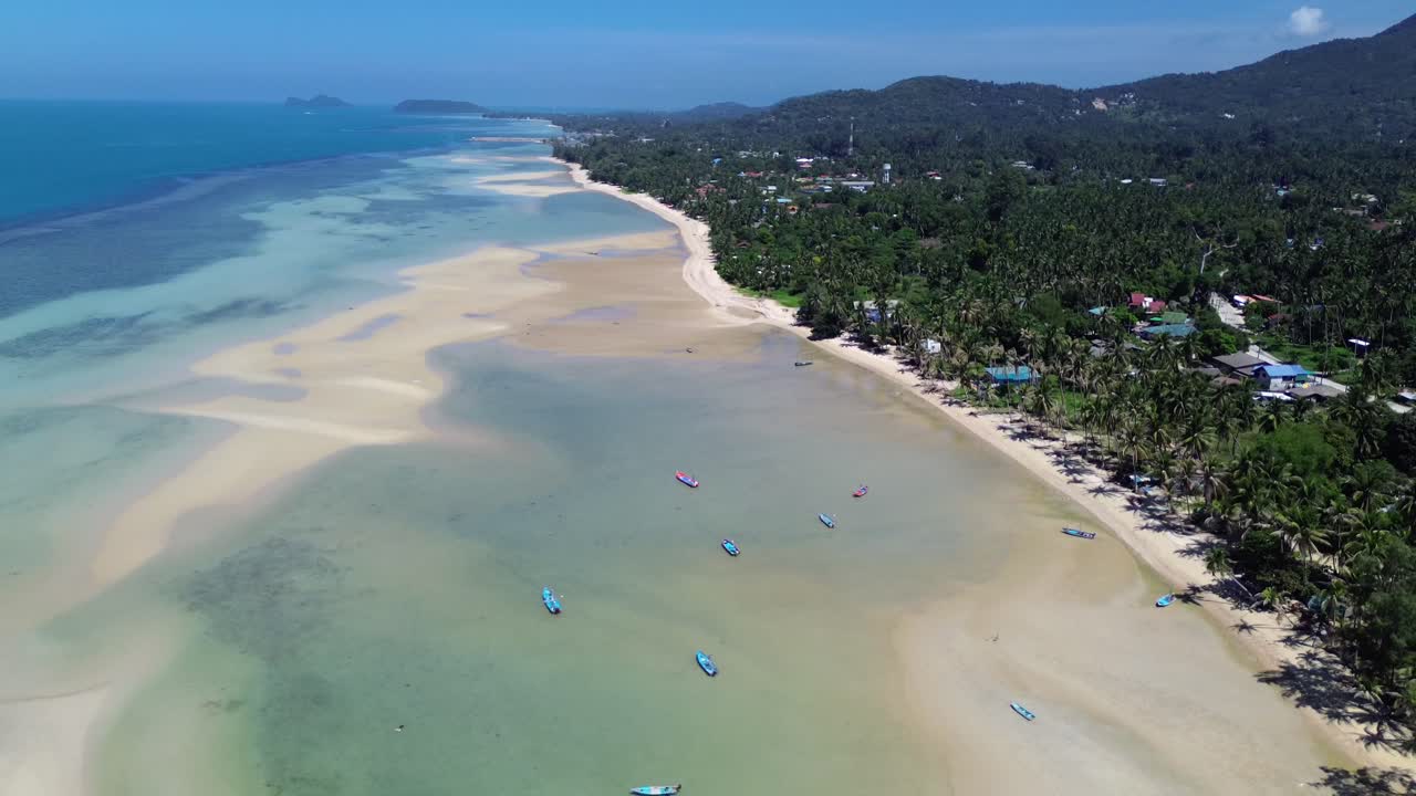 Drone footage of Koh Phangan coastline featuring sandy beaches, turquoise water, seaside bungalows, and local houses surrounded by lush tropical nature in southern Thailand