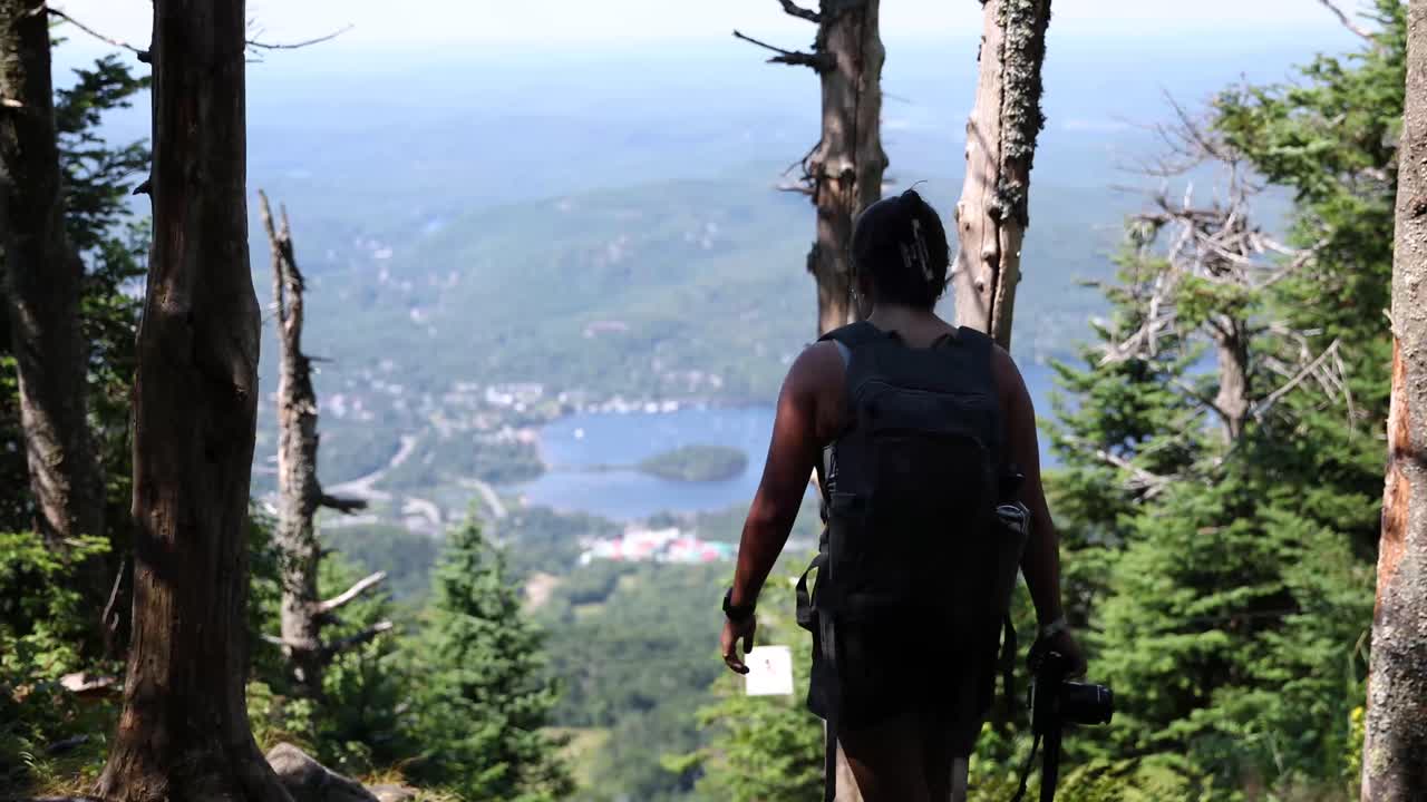 excursionista caminando hacia un claro en un bosque con una hermosa vista desde lo alto del monte