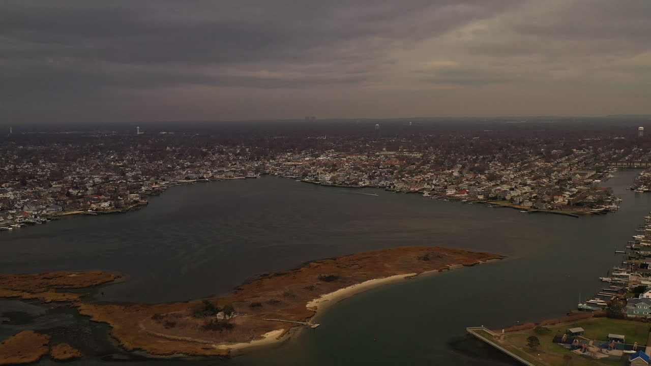 Una veduta aerea dall'alto sulle paludi salmastre a Freeport, NY. La telecamera del drone esegue una panoramica a sinistra sulla palude salmastra in una giornata nuvolosa, con la comunità costiera - l'orizzonte in vista