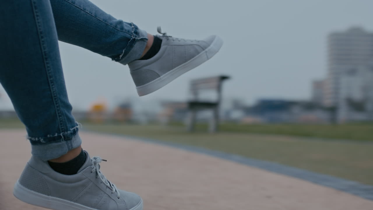 cerrar los pies de una mujer en un tiovivo girando las piernas colgando disfrutando de la diversión en las vacaciones de verano de una adolescente en el patio de la escuela