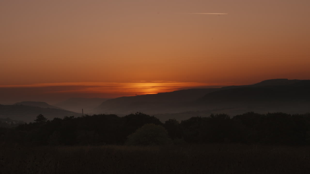 timelapse del amanecer en el horizonte sobre el paisaje del valle de gales con fondo montañoso con niebla baja y árboles