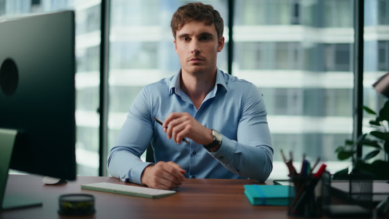 un impiegato perplesso seduto alla scrivania con un computer che guarda da vicino a un punto