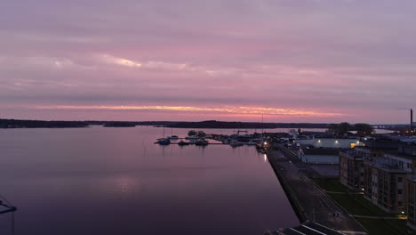 Aerial-view-reveal-of-shipping-dock-by-water-in-Sweden-Slottsholmen-at-sunset-gradient-sky