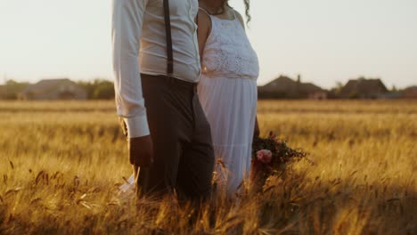 pareja caminando de la mano en un campo de trigo al atardecer