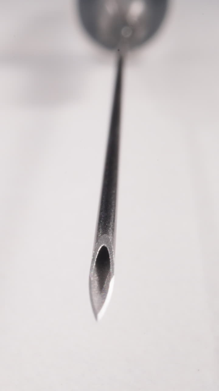 Clean shiny needle of syringe on white background macro view. Medical tests in hospital laboratory. Disposable instrument for cure injection