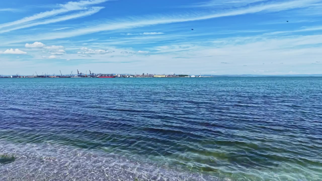 Peaceful ocean with distant ships. Serene view of tranquil blue water and vessels. Quiet maritime landscape showcasing bright sky and scattered ships in distance