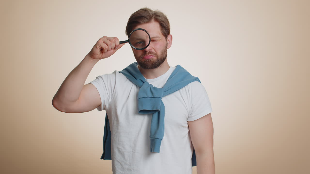 Investigator researcher man with magnifying glass near face looking into camera with big zoom eye