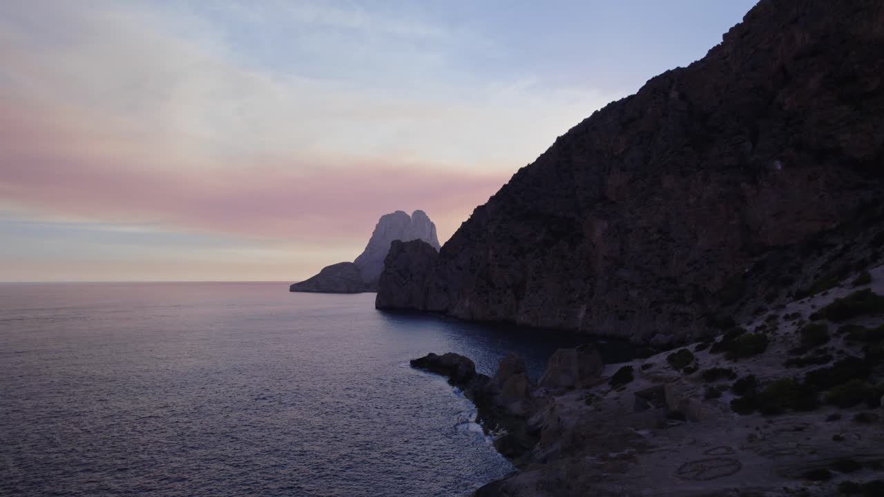 levante con un dron en las montañas delanteras y la costa y en el fondo el océano con la roca es vedra en ibiza