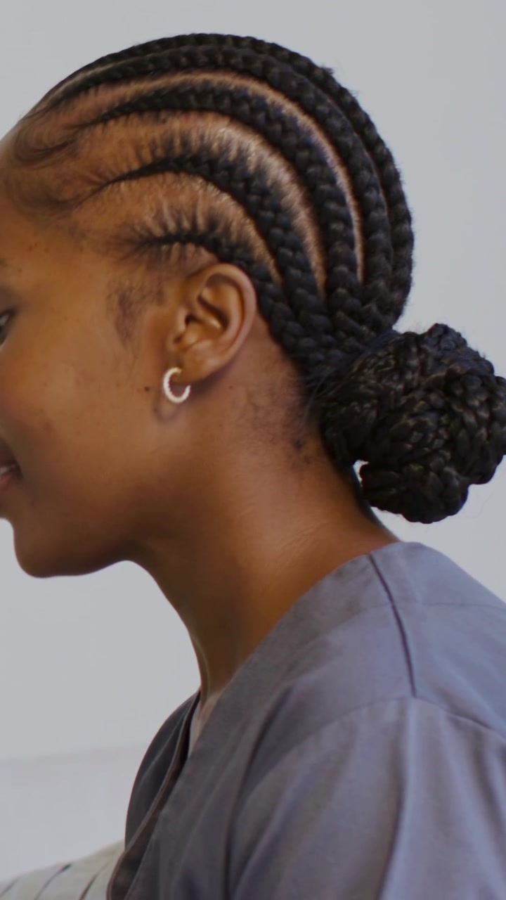 Vidéo verticale : Levant le menton en réponse à un signal hors champ, une femme en blouse médicale parlant dans une clinique, avec un chignon et des créoles.