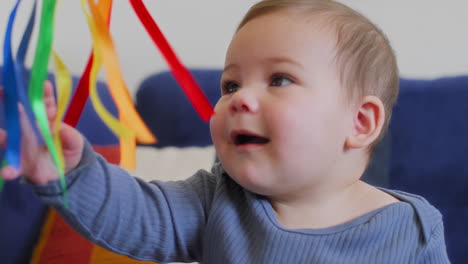 Baby-Spielt-Mit-Regenbogen-Seidenbändern-In-Zeitlupe