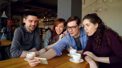 happy students are taking selfie self portrait in cafe, making funny faces and gestures, hugging and laughing. millennials, connection and modern lifestyle concept.