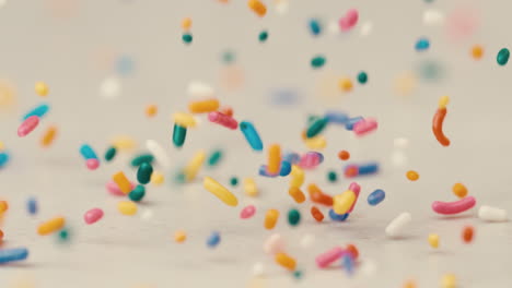 rainbow sprinkles falling and bouncing on white back drop in slow motion birthday party celebrate