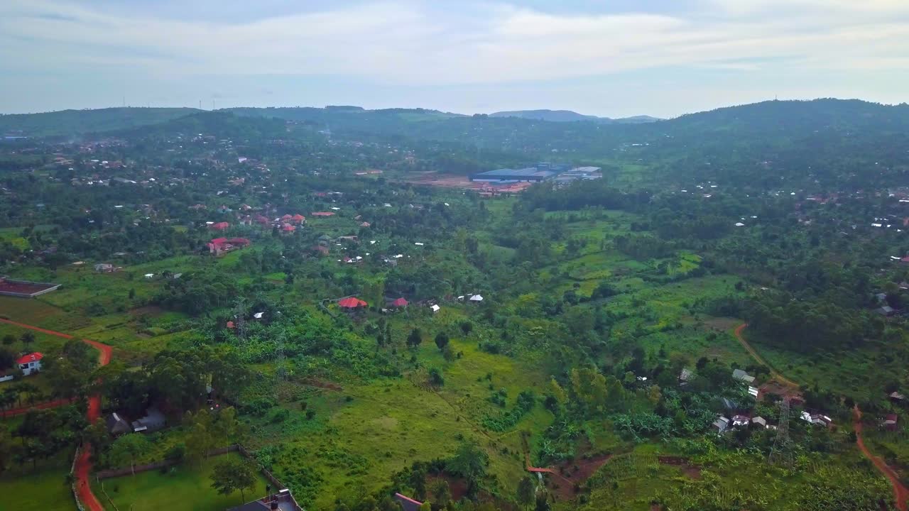 Luftfoto af et nybygget industrianlæg beliggende nær Nilen, der viser fabriksbygninger i et grønt flodlandskab og det omkringliggende landlige terræn i Uganda