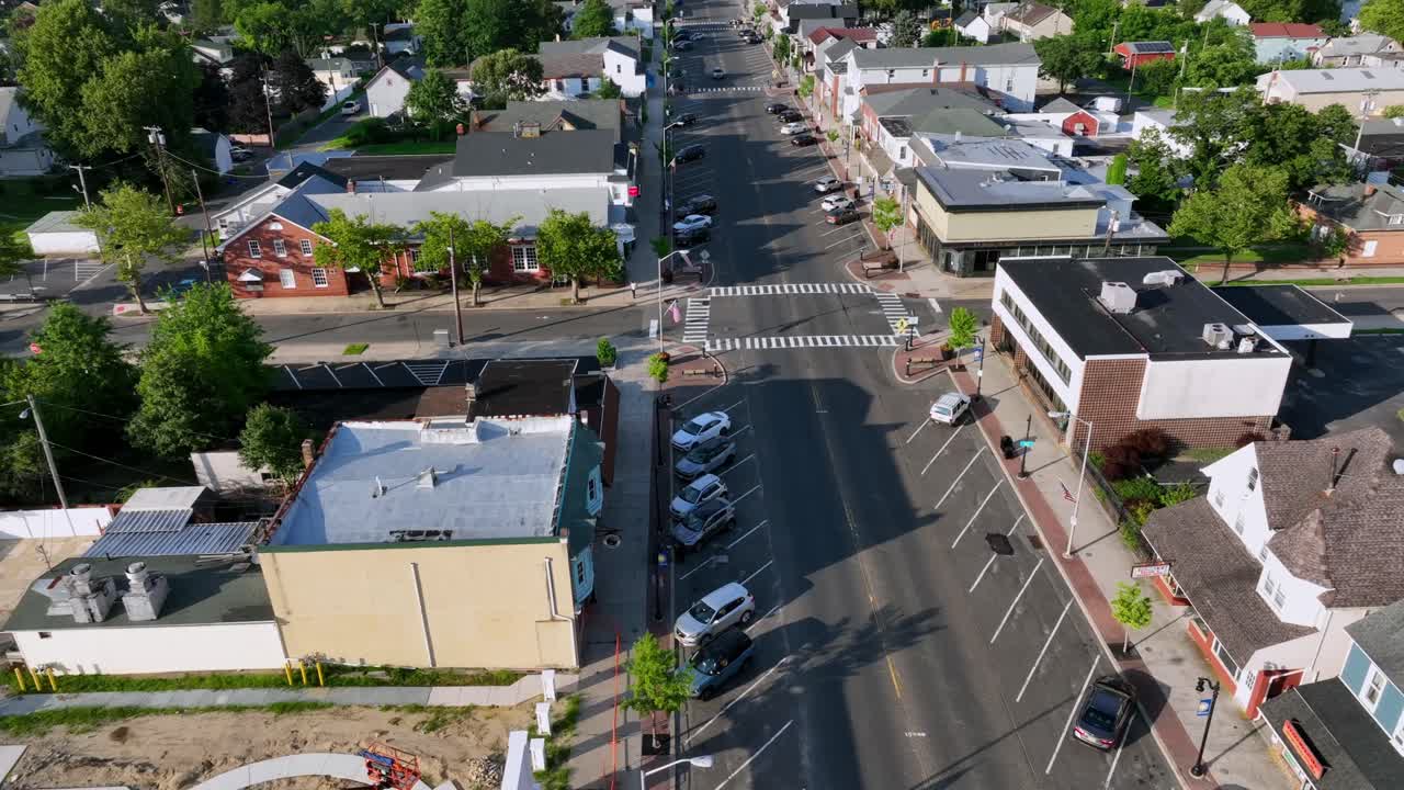 Downtown Egg Harbor City, New Jersey, showing main street, small businesses, parked cars, crosswalks and surrounding residential neighborhood. Aerial top down shot. Car on street