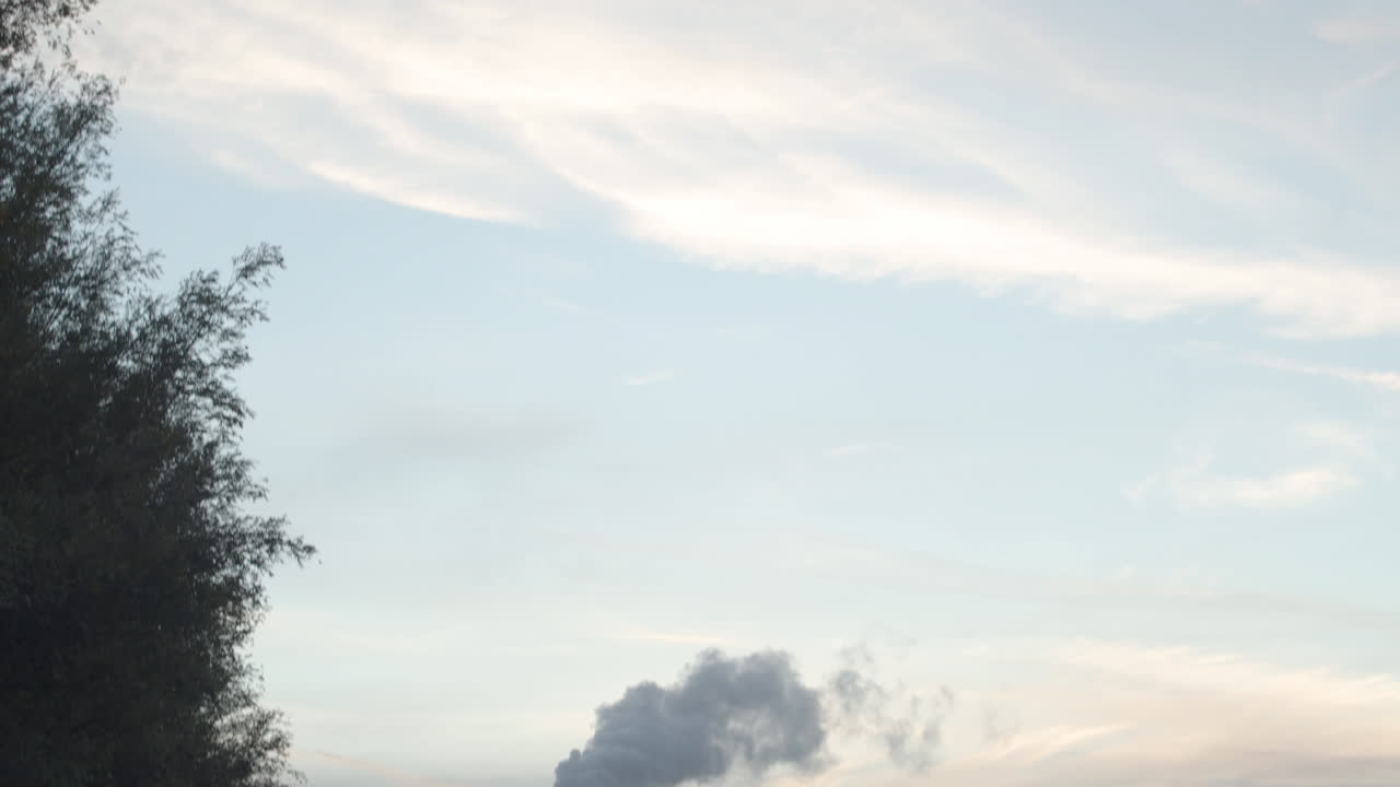 연기가 나는 공장 굴뚝에서 해질녘 흐린 하늘까지 기울어지다