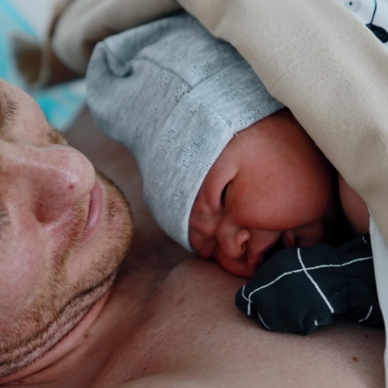 Crying newborn baby lying on the dad's chest after birth. Happy father smiles to camera. Close up