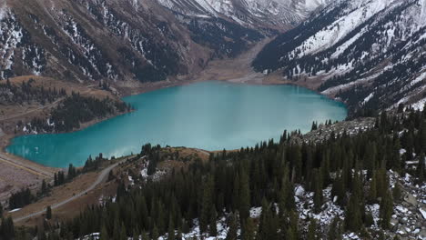 cinematic fly over drone shot of the big almaty lake and the trans-ili alatau mountains in kazakhstan