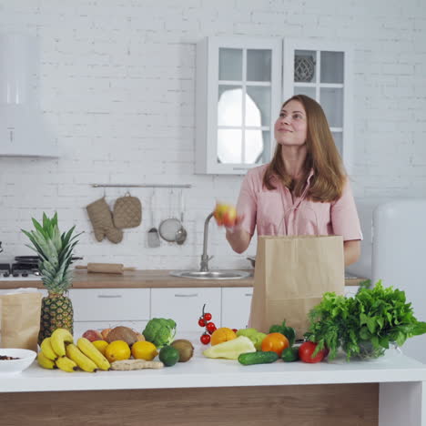 healthy food on a kitchen table. beautiful woman taking out fresh apples from shopping bag. loving mom cares about nutrition.