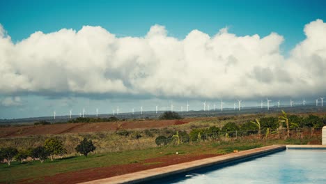 poolside timelapse of windmills in the distance with clouds moving in the sky