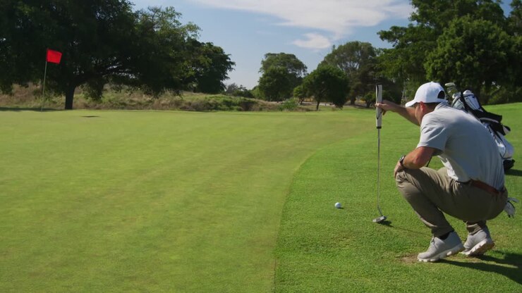 Golfista maschio caucasico inginocchiato su un campo da golf in una giornata di sole