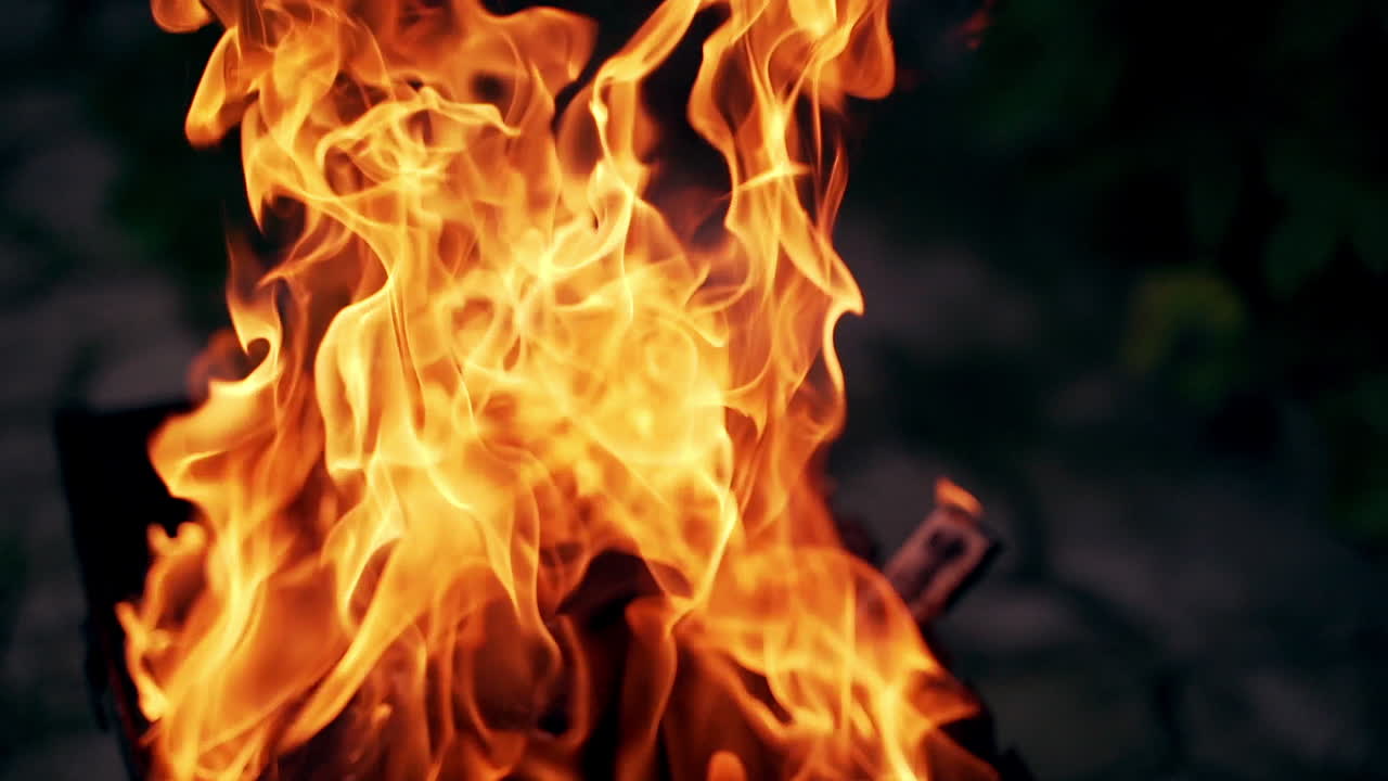 a burning and sparking campfire at night with burning woods.