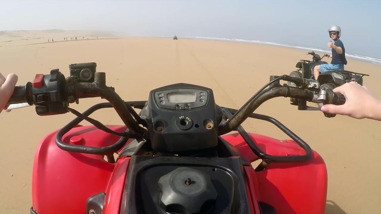 Inquadratura POV Quattro. Gruppo di quad che corrono su una spiaggia deserta in Marocco, con tempo tempestoso.