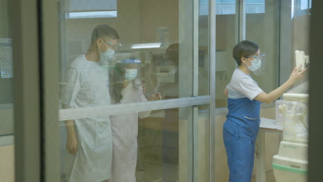 young parents of a new born baby standing outside the nursery with face mask