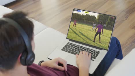 video de una persona sentada en el sofá y viendo un partido de fútbol en una computadora portátil