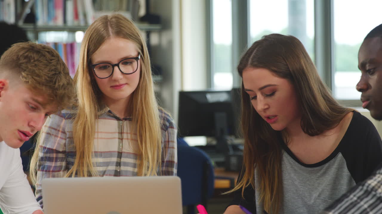 grupo de estudiantes universitarios trabajando en la biblioteca con una computadora portátil