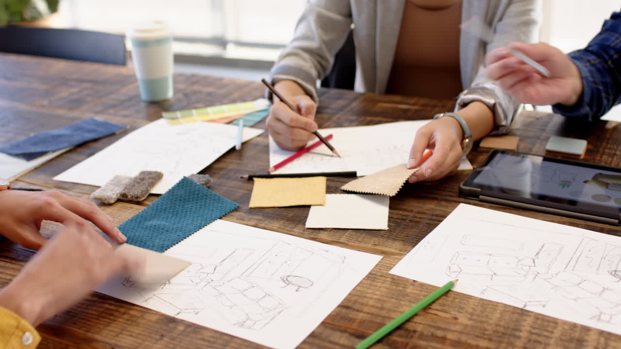 Interior design project, multiracial team discussing sketches and fabric samples together, at office