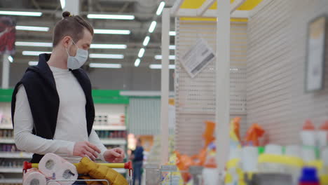 hombre comprando papel higiénico en un supermercado durante una pandemia