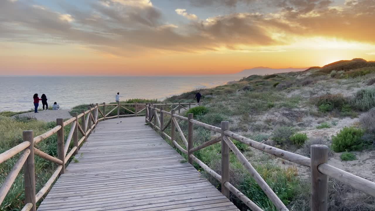 Walking on a wooden path on a southern Spanish beach in Marbella, with stormy skies.