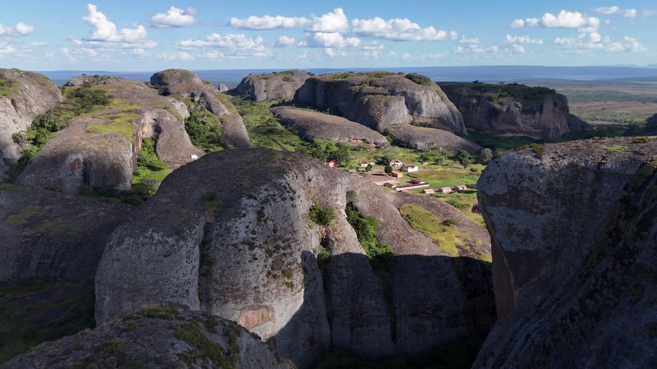Drone footage flying between towering rock walls of Pedras Negras, Angola, revealing deep canyons, sunlight, and shadow across rugged geological formations
