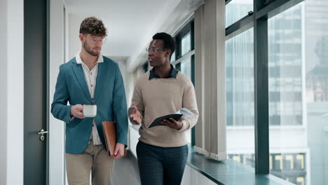 two businessmen walking and discussing work in an office hallway