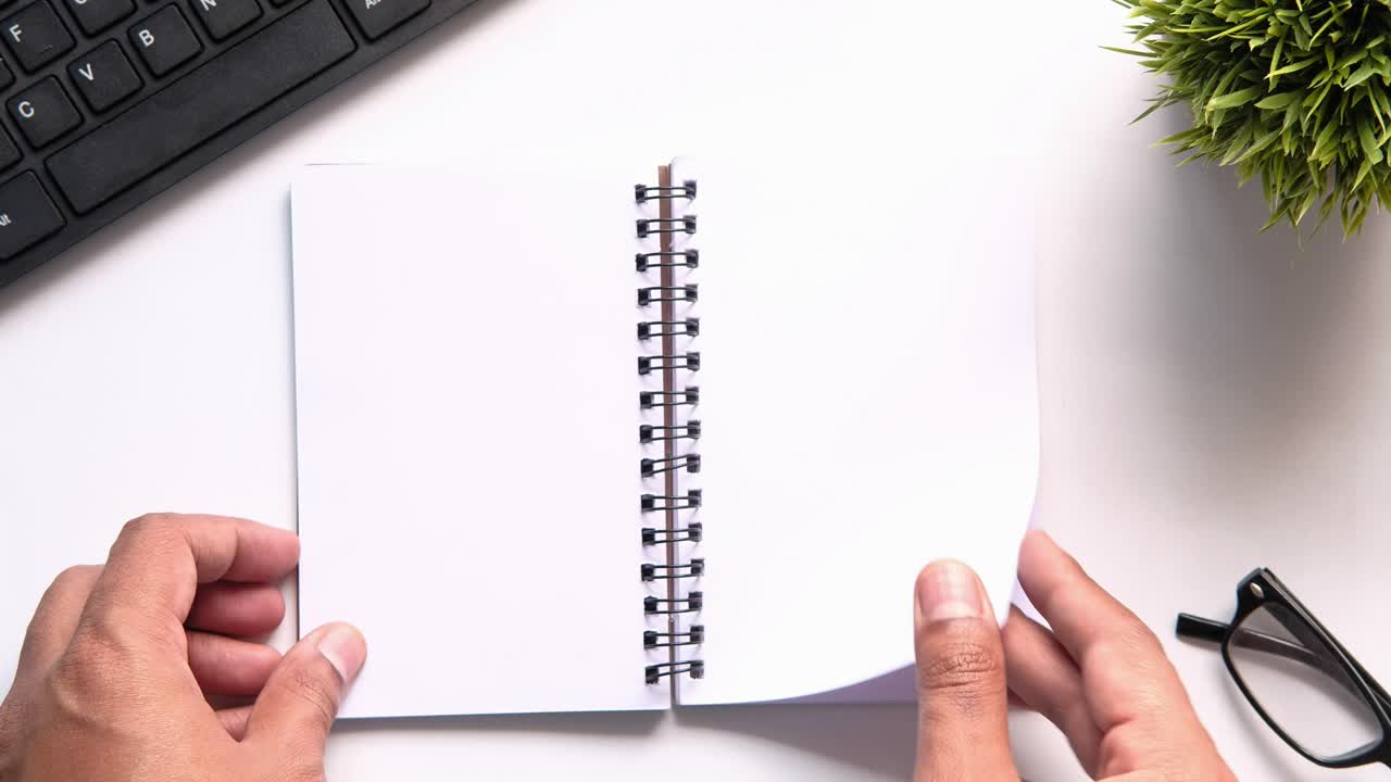 Open Notebook on a Desk with Hands and Accessories